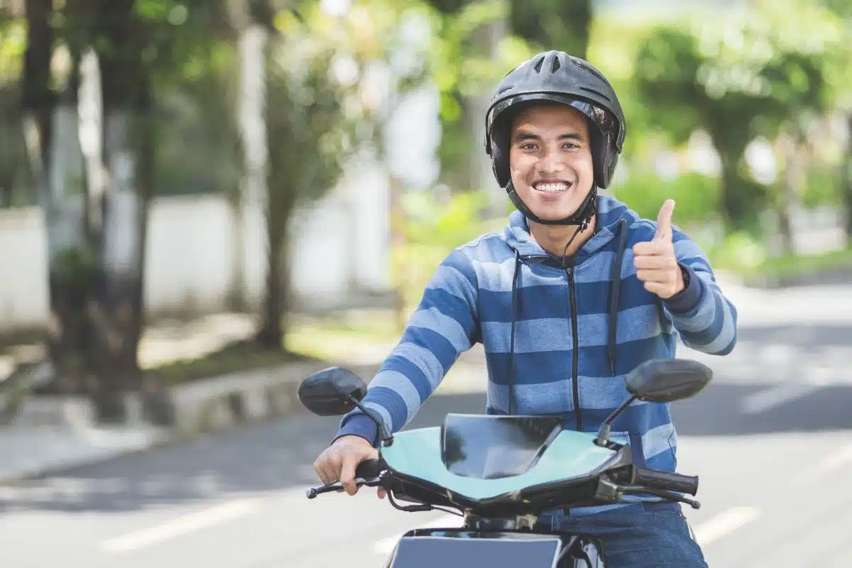 Jeune motard souriant levant le pouce après l'obtention de son permis A1