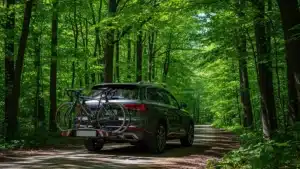 Voiture SUV équipée d'un porte-vélo sur hayon transportant deux vélos de randonnée sur route forestière