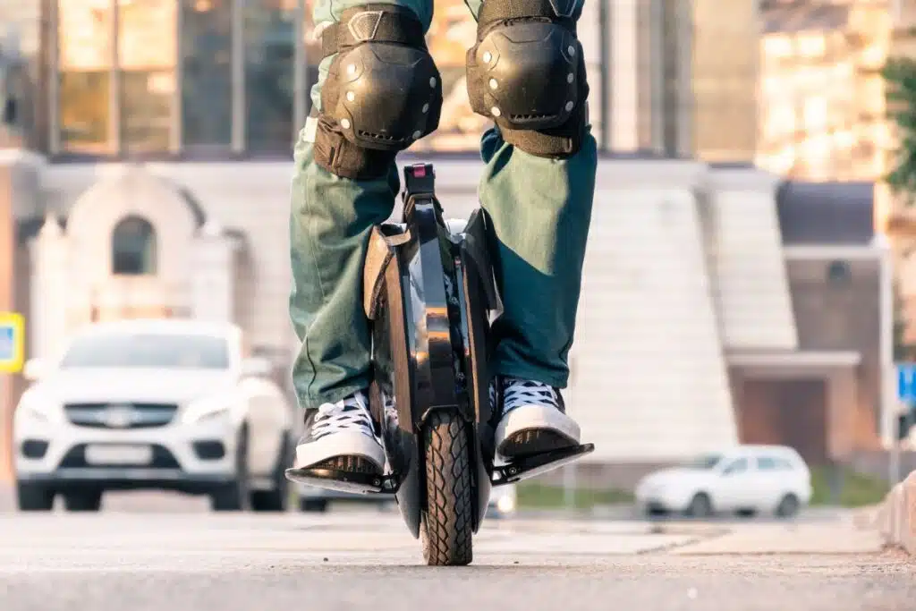 Personne debout sur une gyroroue électrique en ville, avec genouillères de protection