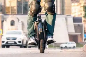 Personne debout sur une gyroroue électrique en ville, avec genouillères de protection