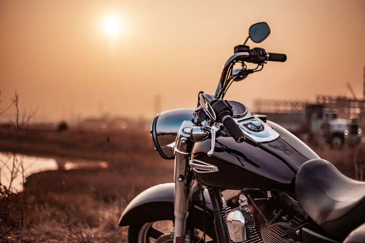 Détail réservoir et guidon d'une moto cruiser Gros plan sur le réservoir chromé et le guidon d'une moto cruiser noire au coucher du soleil
