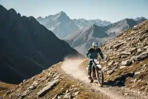Rider sur moto trail tout-terrain traversant un chemin rocheux en montagne
