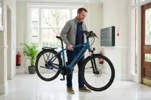 Homme soulevant un vélo électrique de ville dans un couloir d'immeuble