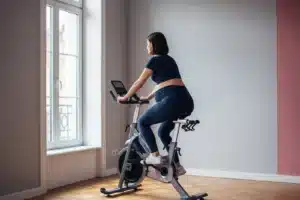 Femme enceinte de 7 mois pédalant sur un vélo d'appartement dans un home gym lumineux - activité physique pendant la grossesse