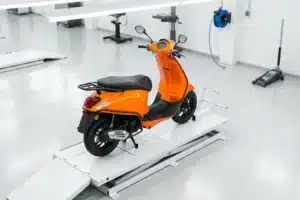 Scooter 50cc orange sur plateforme de contrôle technique en centre agréé, vue plongeante