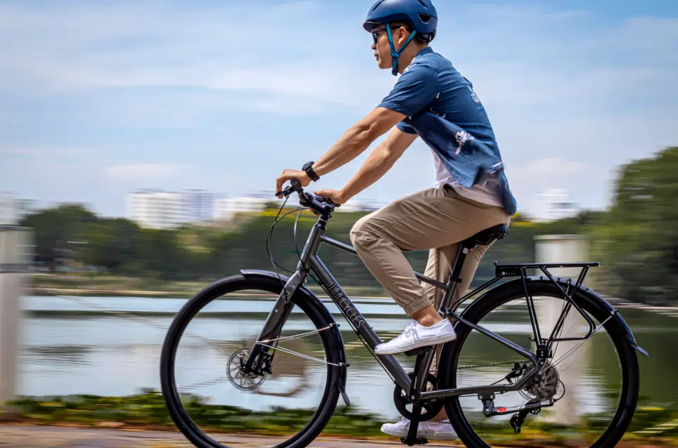 velo debride Cycliste roulant à vive allure sur un vélo électrique le long d'un plan d'eau, illustrant la vitesse d'un VAE débridé