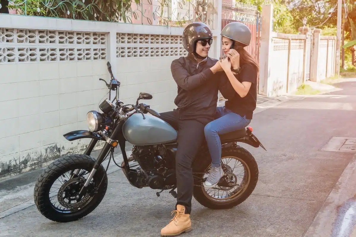 Un homme et une femme casqués près d'une moto stationnée dans une rue